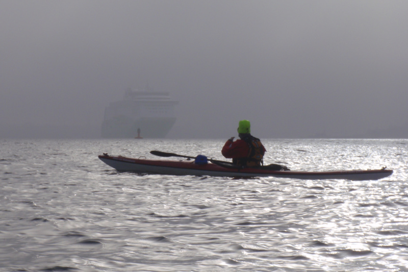 Paddlerin im Nebel an einer Fahrwassertonne, im Nebel im Hintergrund ist eine Fähre erkennbar