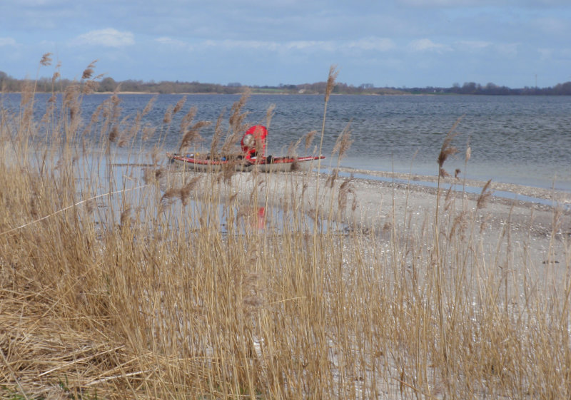 Paddlerin an ihrem Boot am Strand - Gras im Vordergrund